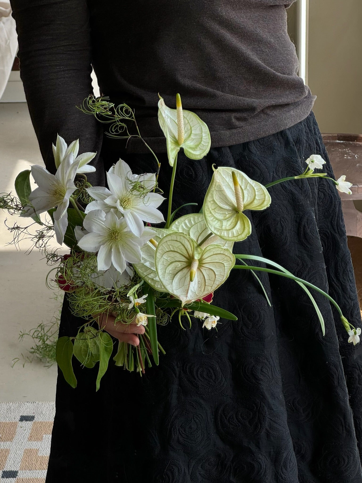 A unique bridal bouquet featuring light green anthuriums, white clematis, and delicate greenery, creating a fresh and modern design.